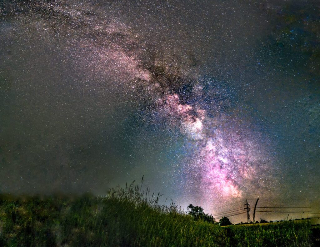 Astrofotografie Milchstrasse fotografiert mit Strommasten im Hintergrund.